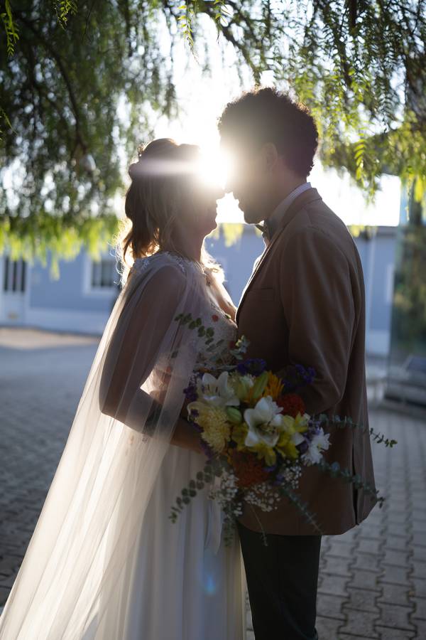 Couple backlit by the sun, holding the bouquet — wedding in Sintra
