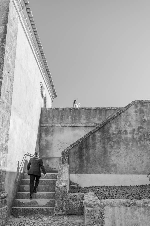 Groom climbing old stone steps — wedding in Óbidos
