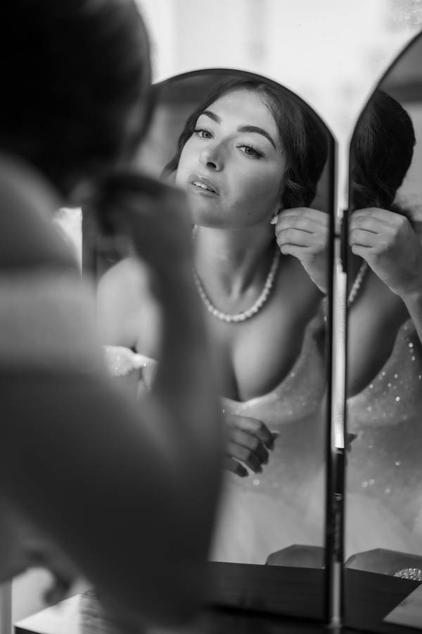 Bride putting on her earrings in the mirror — wedding in Sintra