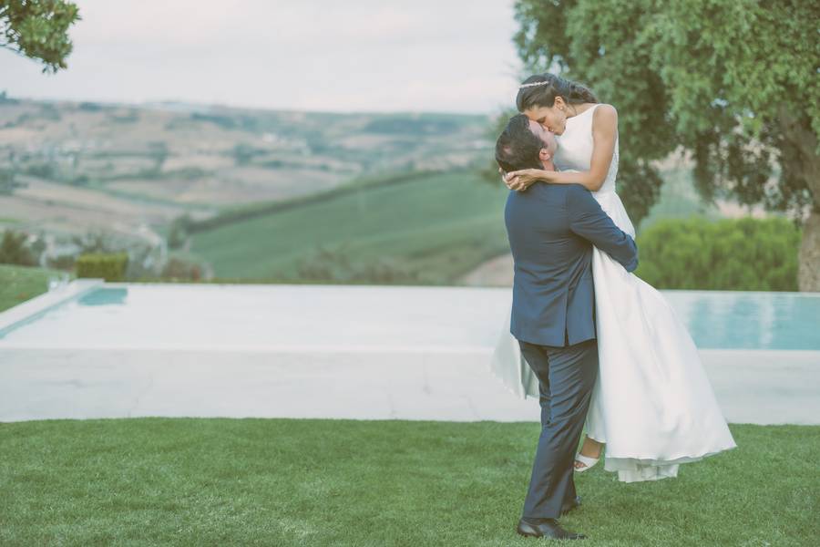 Groom lifting the bride by the pool overlooking the hills — wedding in the Douro Valley