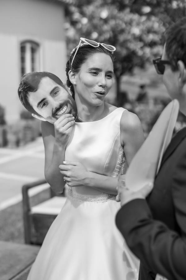 Bride laughing with a mask of the groom — wedding in Cascais