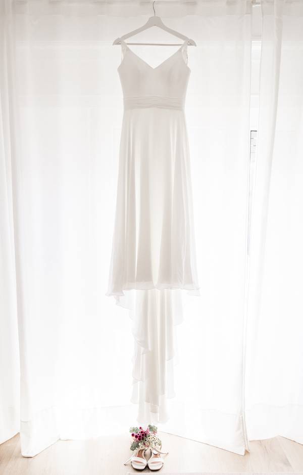 Wedding dress hanging in the window — wedding in Arrábida